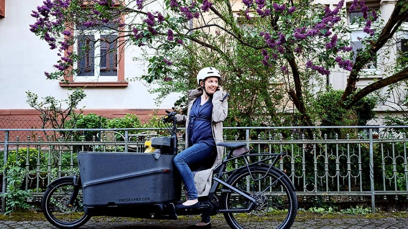 Eine JobRadlerin auf dem Lastenrad blickt zurück auf ihr Handy